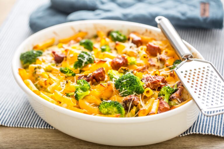 A bowl of mac and cheese topped with bacon and broccoli.