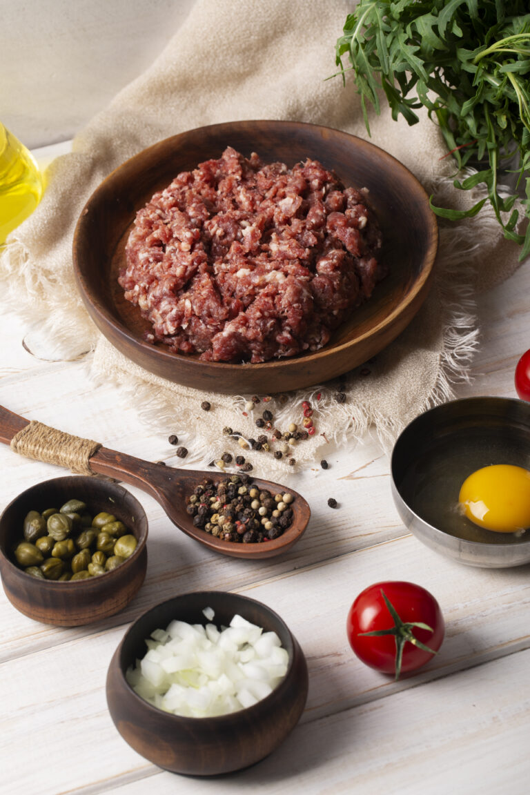 Ground bison meat on a wooden cutting board with seasonings.