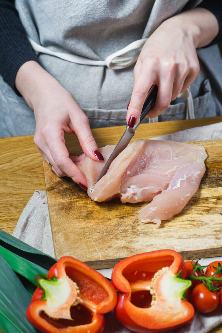 A chef pounding chicken breasts with a mallet.