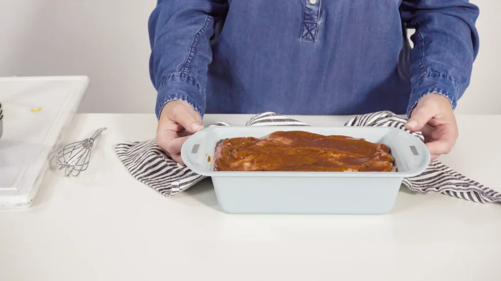 A chef gently shaping a meatloaf mixture on a baking tray