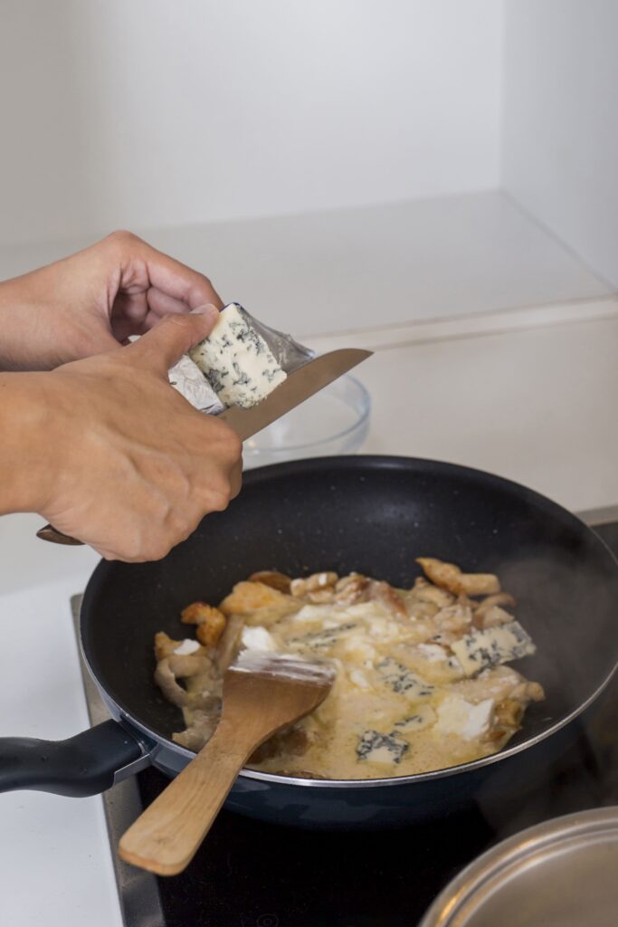 Cajun Alfredo Sauce simmering in a pan with a wooden spoon