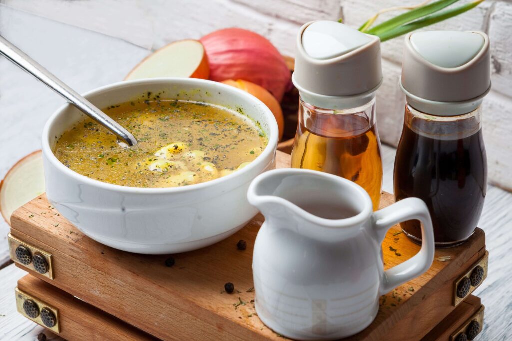 A pot of simmering chicken stock with vegetables and herbs