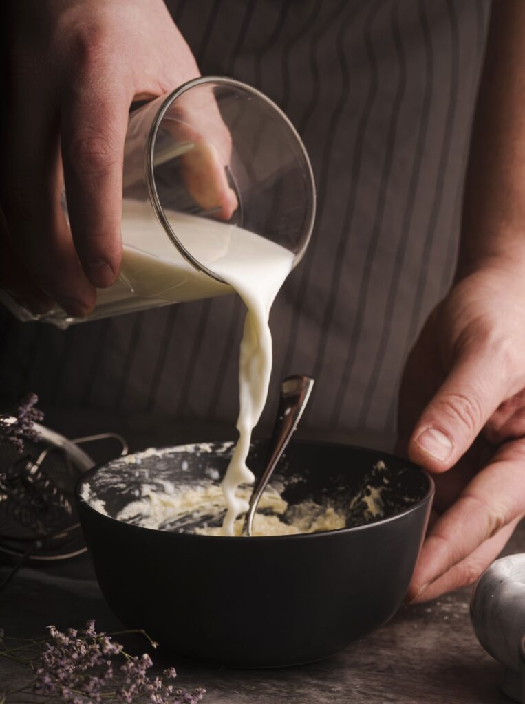  A chef stirring freshly made Alfredo sauce in a pan.