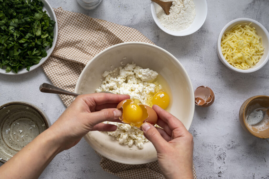 A layered lasagna being prepared with a smooth ricotta and egg layer.
