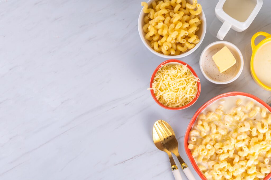 Various cheese, pasta, milk, and butter arranged on a kitchen counter.