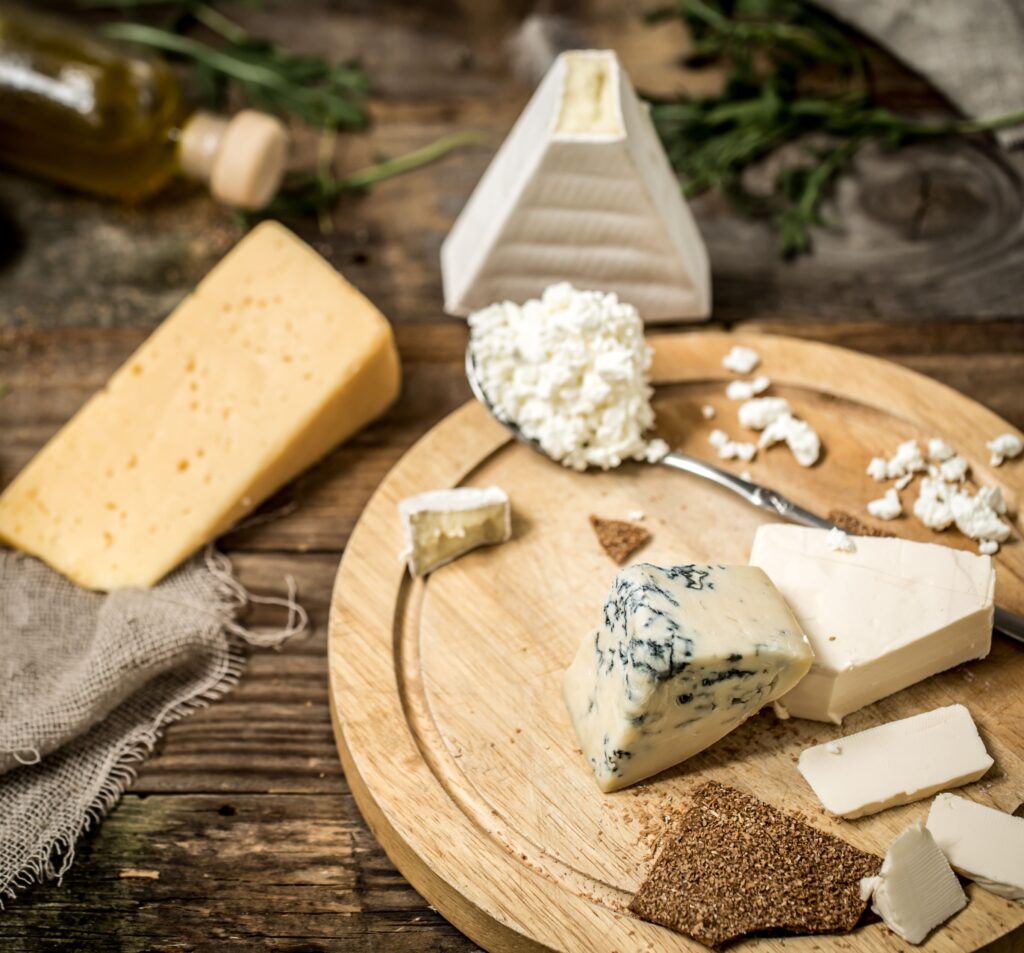 A variety of cheeses, including Parmesan, Romano, and Asiago, on a wooden platter.