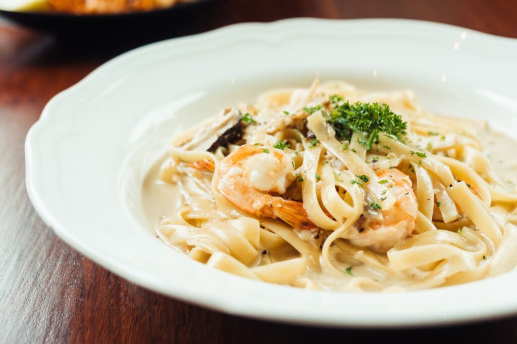 Bowl of creamy Cajun Alfredo Sauce with pasta and grilled shrimp