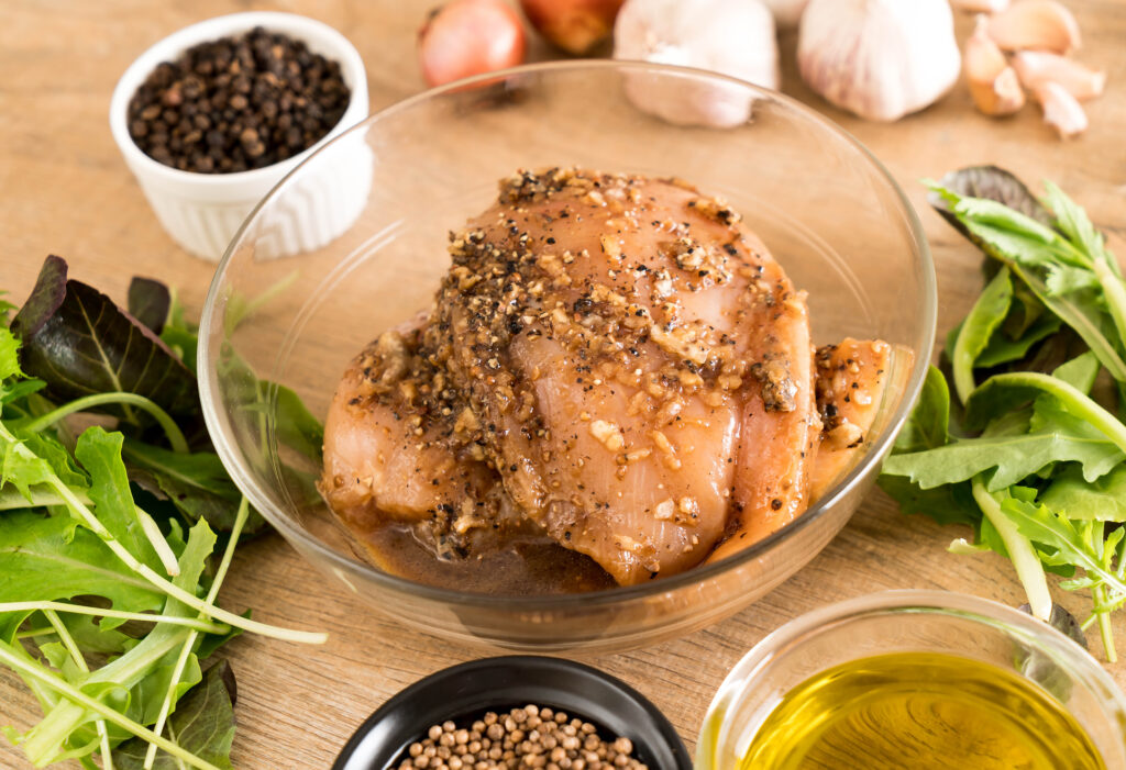 Chicken breasts soaking in a bowl of lemon-garlic marinade.