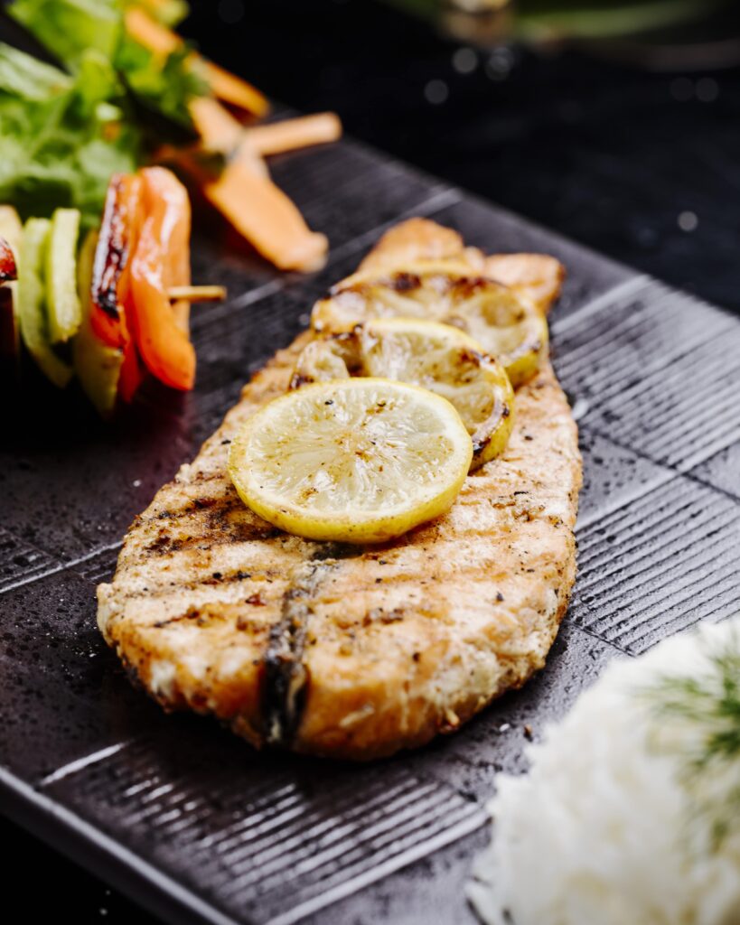 Grilled rockfish fillets with herbs and lemon wedges.