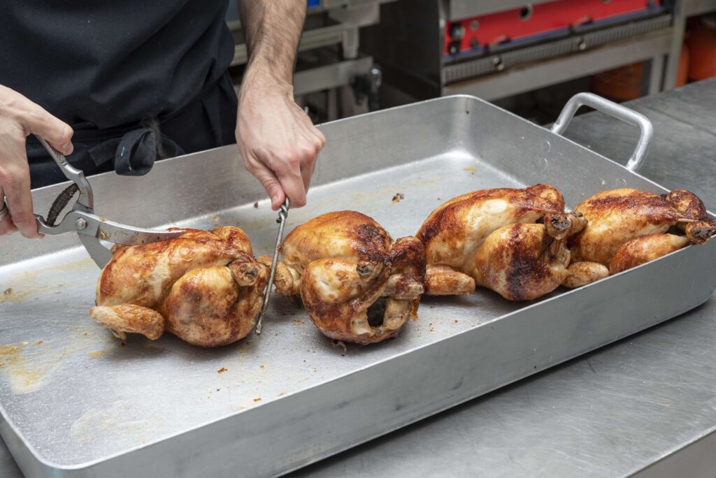 Freshly roasted chickens on a rotisserie in a Costco kitchen