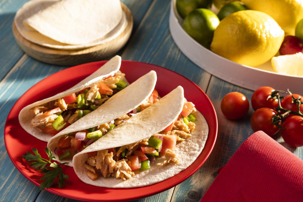 tacos with cabbage slaw and lime wedges on a plate.