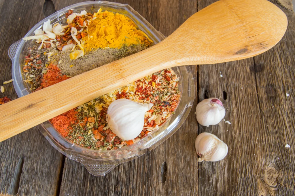 Individual spices and herbs arranged neatly on a wooden table.