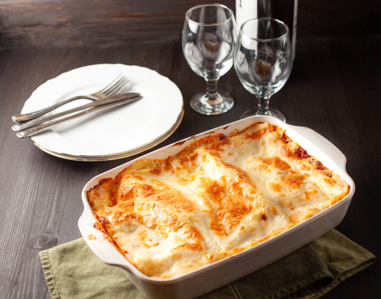 A perfectly layered lasagna with golden, bubbly cheese on top, served in a rectangular glass dish.