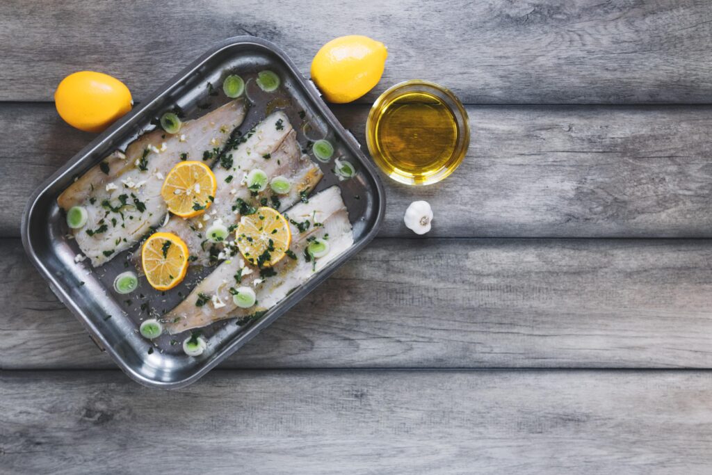 Rockfish fillets soaking in lemon water with sliced lemons floating on top.