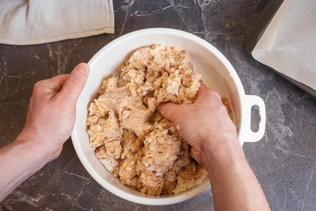 Hands mixing meatloaf ingredients in a large bowl 