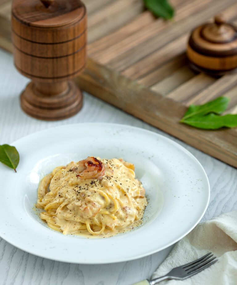 Plate of fettuccine pasta with Alfredo sauce served with fresh herbs.