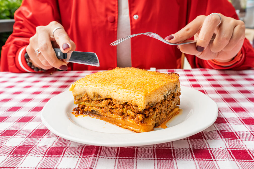 lasagna part with golden cheese crust, fresh basil garnish, and a serving spatula.