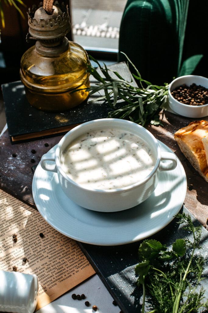 A close-up of fresh herbs like basil, parsley, and rosemary beside a creamy sauce.