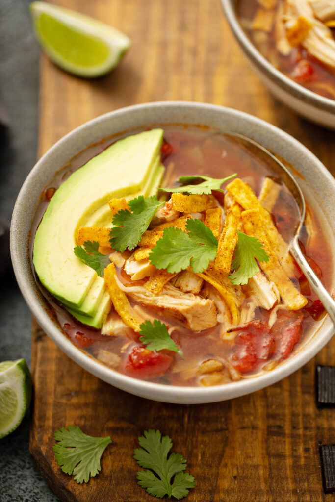 A bowl of chicken tortilla soup topped with tortilla strips.