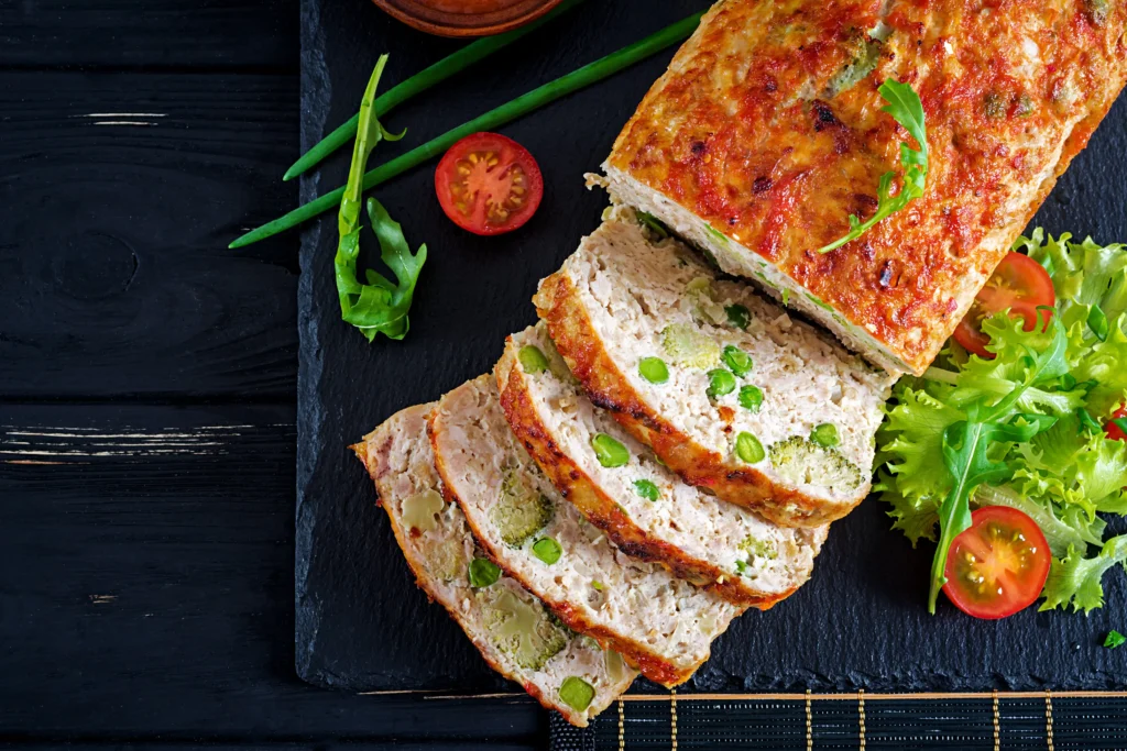 A perfectly baked meatloaf garnished with herbs on a wooden board