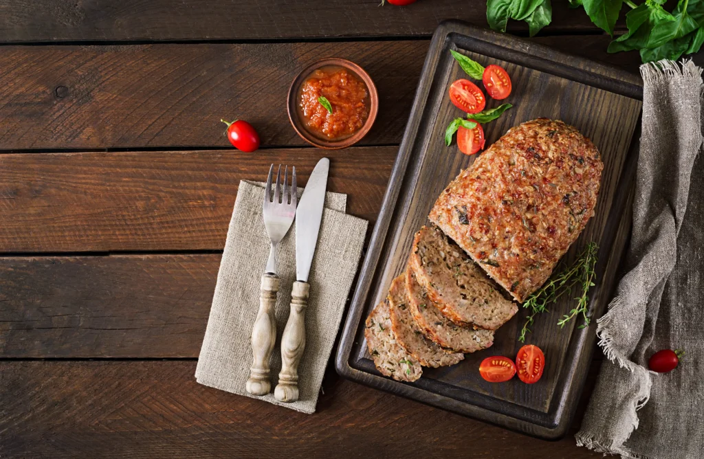 A juicy homemade meatloaf sliced on a wooden cutting board